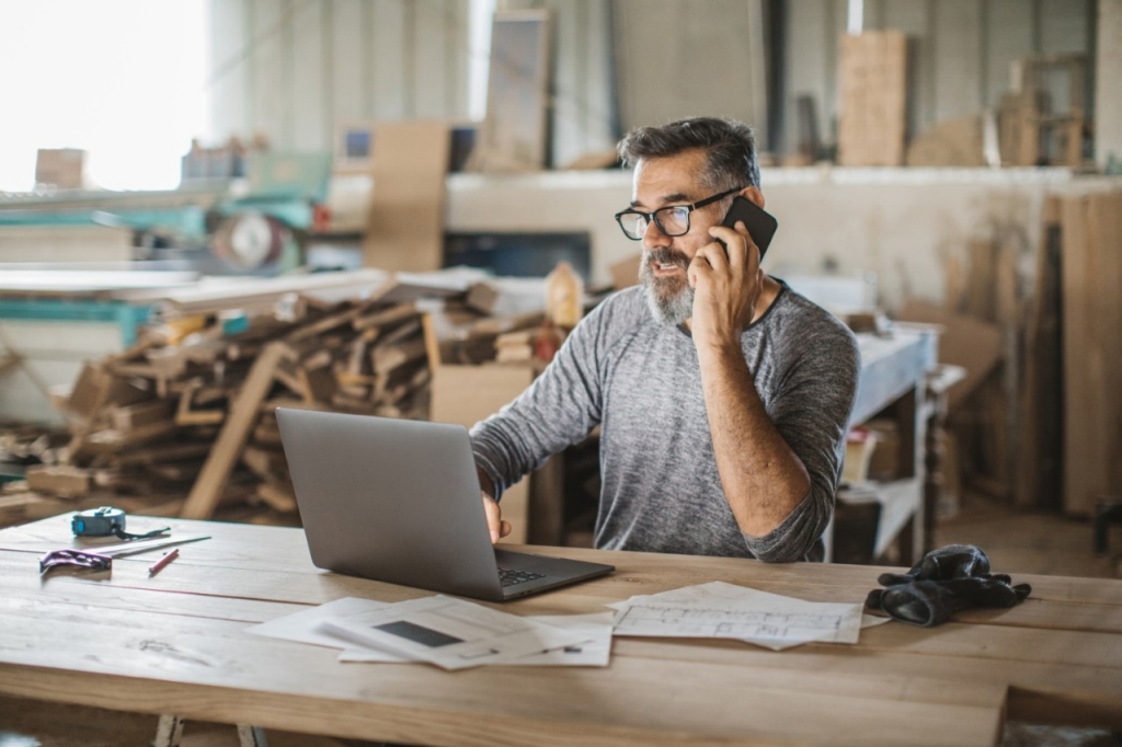un hombre trabajando a la vez con el ordenador y hablando por el móvil