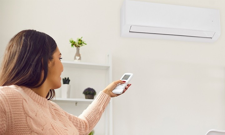 Mujer utilizando el aire acondicionado en modo calor en invierno