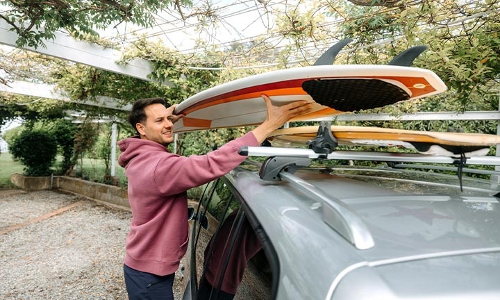 Chico colocano la tabla de surf para llevarla en el coche