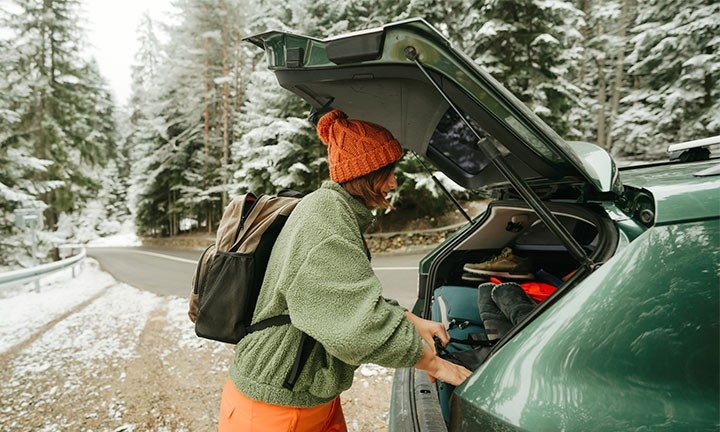 Mujer preparando equipamiento para un viaje de invierno en coche