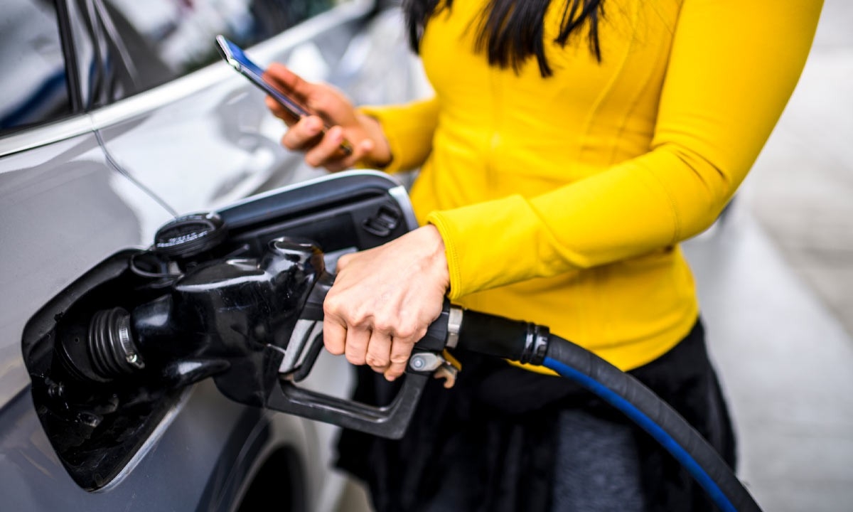 Mujer usando el móvil en una gasolinera